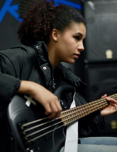 A young person playing bass guitar.