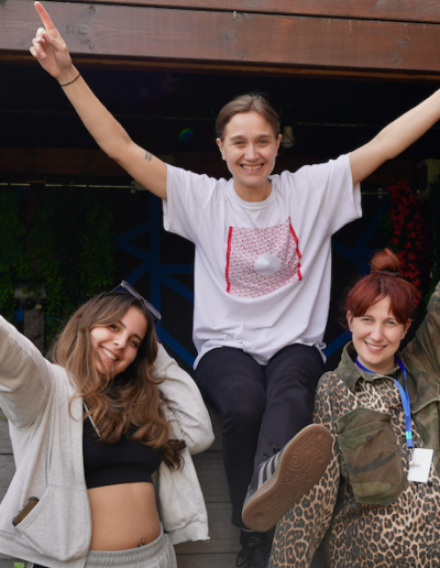 A group of three people all smiling at the camera with their hands up in the air.